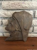 Front profile of hand-carved wooden fisherman head plaque, showing textured carving and signed front side.