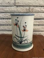 Front angle view of the tall pottery pillar vase showing hand-painted floral design on white background with a muted blue rim and base detailing.
