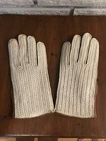 Front side of gloves showing cream knitted fabric covering the back of the hand and fingers.