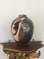 Front and side views of oval-shaped Raku pottery vase with abstract iridescent glaze in green, purple, black, cream, and brown.