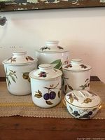 Front view of all five Royal Worcester ceramic canisters with Evesham pattern on a table