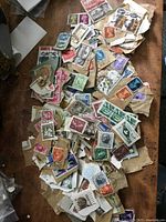 Overview of various postage stamps scattered on a surface, showing different colors and partial papers still attached.