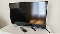 Front view of Best Buy 32-inch LCD TV with remote placed in front