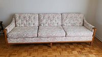 Front view of the floral upholstered Chesterfield sofa with three cushions, showing full length and wood base.