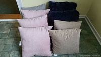 Eight assorted throw pillows stacked, showing variety in color and texture.