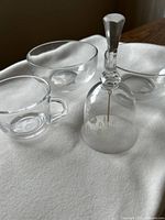 Two glass bowls and one glass bell with handle arranged on fabric.