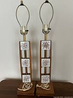 Full front view of two tall mid-century modern lamp bases with ceramic and wood design on wooden surface