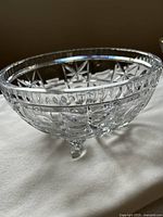 Side angle showing the detailed cut glass star pattern and three-footed base of the crystal bowl.
