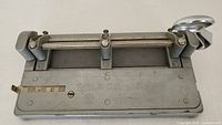 Top view of the gray Wilson Jones Hummer manual paper punch showing the lever arm, adjustable metal guides, and engraved brand name with visible scratches and wear marks.