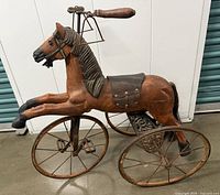 Full side view of the antique wooden horse velocipede showing overall condition, structure, and metal wheels.