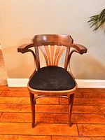 Front view of the Art Deco style wooden chair showing its curved armrests, fanned vertical back slats, and black cloth seat.