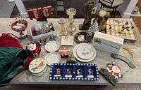 Overview of all Christmas decorations spread on a table showing candlestick holders, plates, Santa figurines, a wooden 'Peace' sign, and assorted holiday decor.