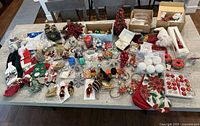 Overview of table displaying a large variety of Christmas decorations including stockings, ornaments, and shelf decor.
