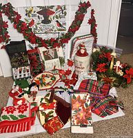 Full view of the poinsettia-themed Christmas decor lot showing garlands, cloth napkins, pot holders, centerpiece, cookie jar, and other kitchen linens.