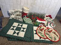 Full view of Christmas lot including vintage holly leaf glasses, various textiles with holly leaf and Christmas motifs, ceramic Santa boot vase, and glass candy dish.