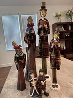 Five large Victorian-style Christmas caroler figurines arranged together showing their height and detail.