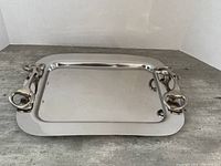 Heavy metal serving tray shown from an angle to highlight shape and handles