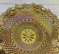 Top view close-up showing diamond texture and central starburst design of amber carnival glass dish.