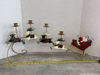 Full view of the metal Santa and reindeer candle holder showing the entire length and design with measuring tape for scale.