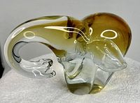 Side view of Murano style amber brown glass elephant figurine on white towel.