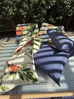 Four outdoor pillows and two seat cushions arranged on outdoor furniture under natural light showing designs and condition