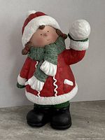 Full view of the figurine showing the girl in red winter coat, black boots, holding a snowball