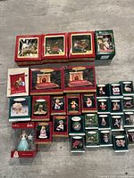Photo showing entire lot of assorted Hallmark and Carlton Christmas ornaments in original boxes arranged on a floor.