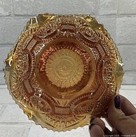 Bottom view of the bowl showing the embossed Twins pattern within the marigold iridescent glass and ruffled edge.