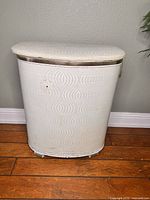 Front view of the vintage ivory vinyl laundry hamper with metallic trim showing geometric pattern and minor marks.