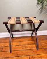 Front view of the vintage wooden luggage rack with three woven fabric straps and curved legs.