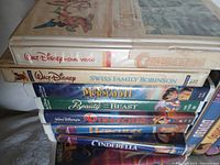 Stack of Disney VHS tapes showing titles Candleshoe, Swiss Family Robinson, The Little Mermaid II, Beauty and the Beast.