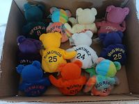 Top-down view of eleven Bamm Beano plush bears in a box, showing various colors and player jerseys