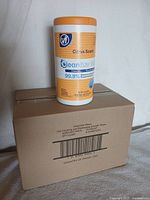 Photo of a single canister of Cleantize disinfectant wipes with citrus scent on top of the brown cardboard box.