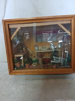 Wooden diorama box with glass front showing interior farm house scene with miniature furniture and plants