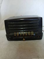 Front view of the Emerson vintage radio showing speaker grille, frequency scale, and control knobs with one knob missing