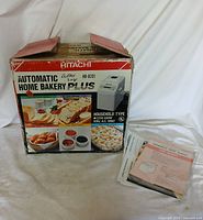Original box of Hitachi Automatic Home Bakery Plus HB-B201 with clear labeling and images of bread, showing age and box damage.