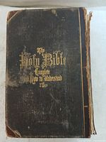 Front cover of the Bible showing worn and damaged dark hardcover with gold embossed title text