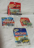 Photo of four Johnny Lightning die-cast cars in original packaging showing Speed Racer, Scooby Doo Machine, Grateful Dead, and Monopoly themed cars.