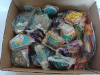 Photo showing a box filled with 21 vintage kids meal toys in original plastic packaging, assorted brands visible including Denny's and Burger King.