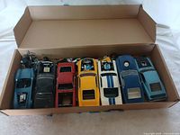 Box containing five Mustang model cars organized side by side with open hoods and visible engine details.