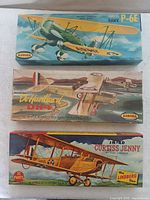 Three vintage Aurora model airplane kits in original illustrated boxes: Curtiss Hawk P-6E (green biplane), DeHavilland DH4, Curtiss Jenny (yellow biplane)