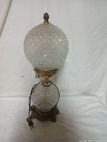 Full view of the vintage nightstand lamp showing two textured cut glass globes, brass base with ornate floral patterns, power cord and plug visible