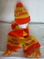 Photo showing one of the Pepsi Challenge hats with pom-pom and scarf laid out on a flat surface with mannequin head