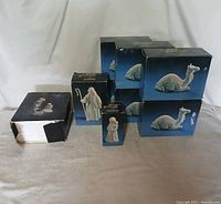 Group photo of all boxed porcelain figurines including 6 camels, shepherd boy, shepherd, and nativity set of baby Jesus with parents.
