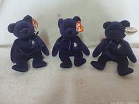 Three purple 'Princess' Ty Beanie Babies shown sitting side by side. Each bear features a silver embroidered crown on chest.