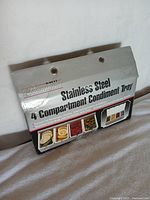 Original box packaging showing product name and a photo of the condiment tray with food items in each compartment.