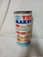 Photo of original cylindrical Tinkertoy Toy Maker container with colorful vintage label showing assembled toy examples.