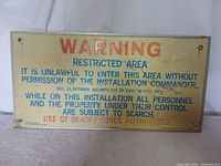 Front view of the vintage metal warning sign showing printed text and condition details.