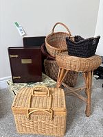 Photo showing all items together: various wicker baskets, wicker stool, wooden lap writer and memory box on grey carpet, against white wall