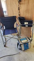 Pair of folding padded beach chairs in navy blue with silver metal frames, and an Outbound soft cooler bag in front